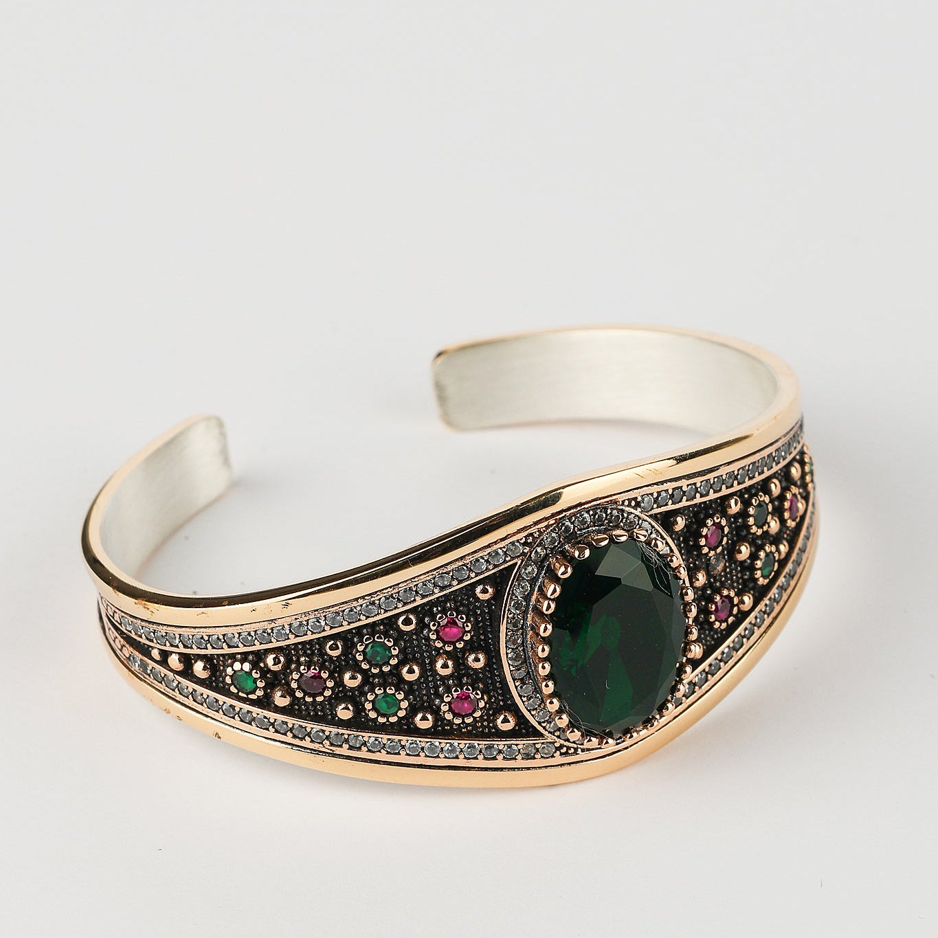 Decorative bracelet with green gemstone and colorful stones on a white background