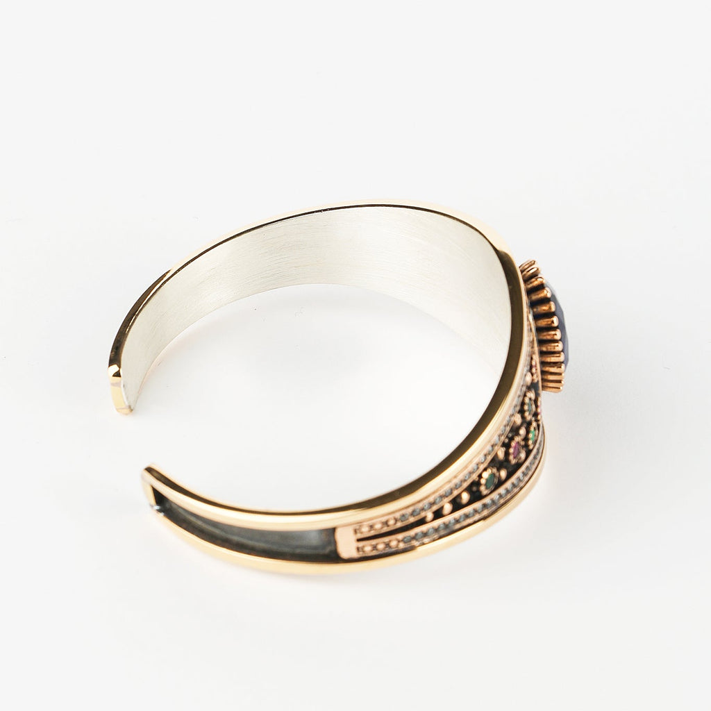 Gold and silver bracelet with a clear stone on a white background