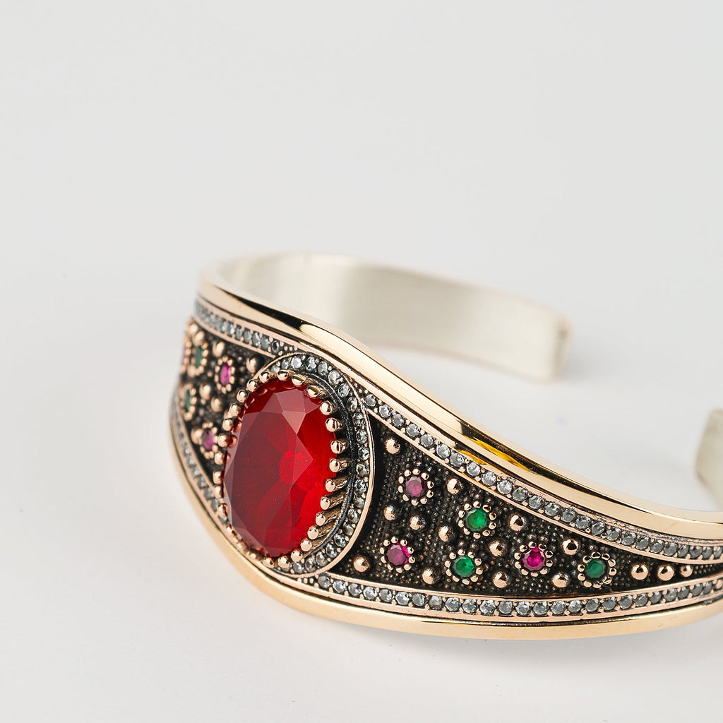 Decorative bracelet with a red gemstone on a light gray background