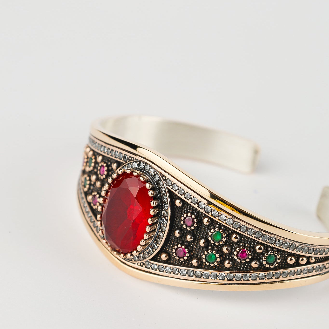 Decorative bracelet with a red gemstone on a light gray background