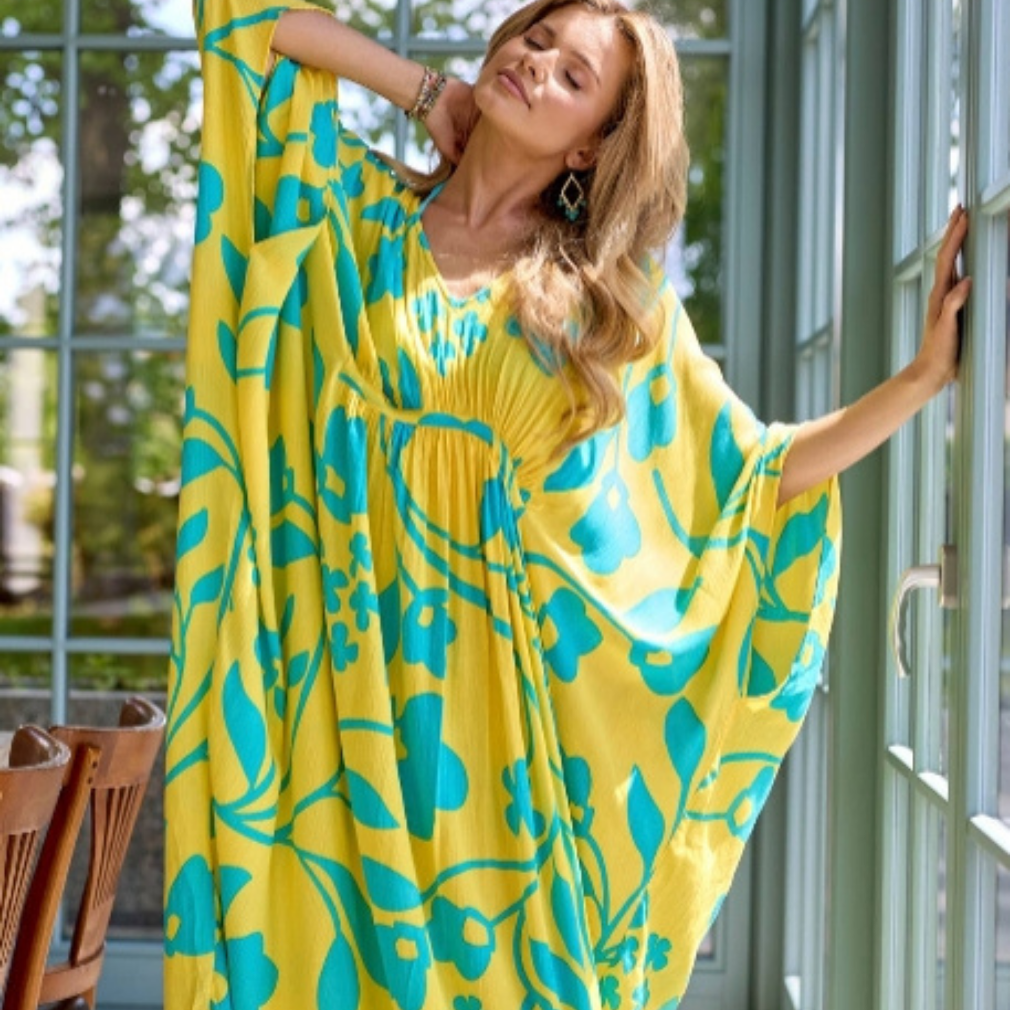 Woman wearing a yellow and blue patterned dress standing indoors.