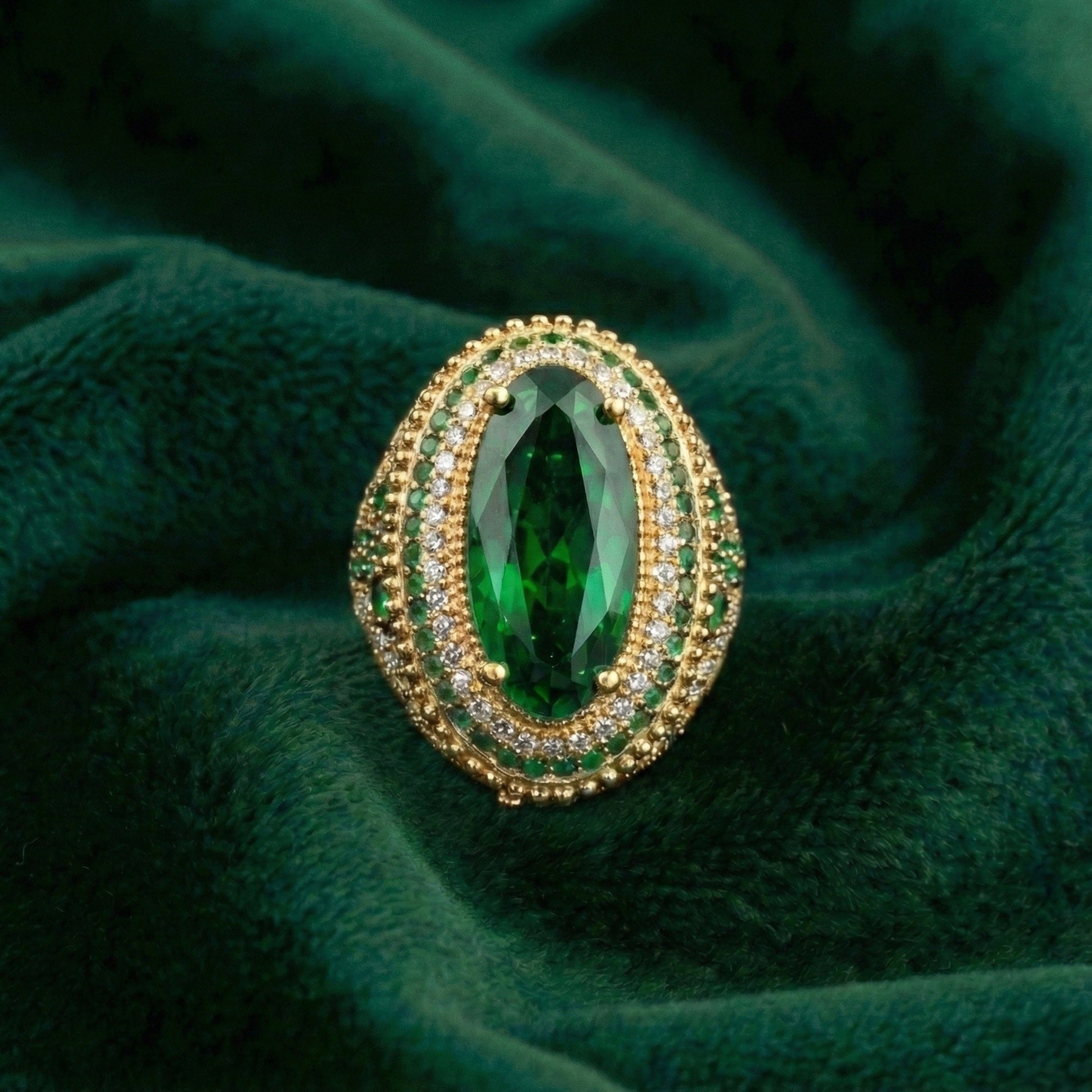 Gold ring with a large green gemstone on a green fabric background