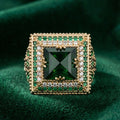 Gold ring with a central green gemstone on a green fabric background