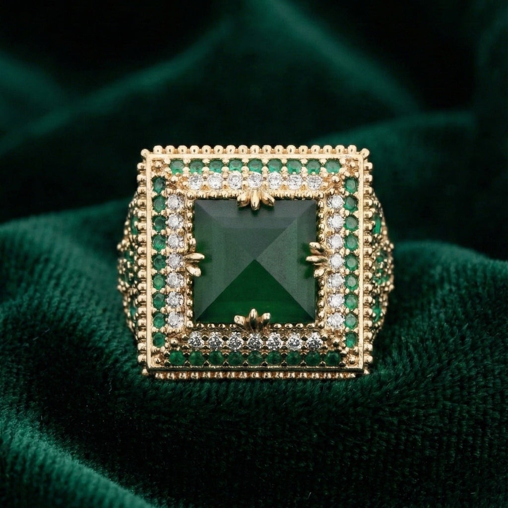 Gold ring with green gemstone on a green fabric background