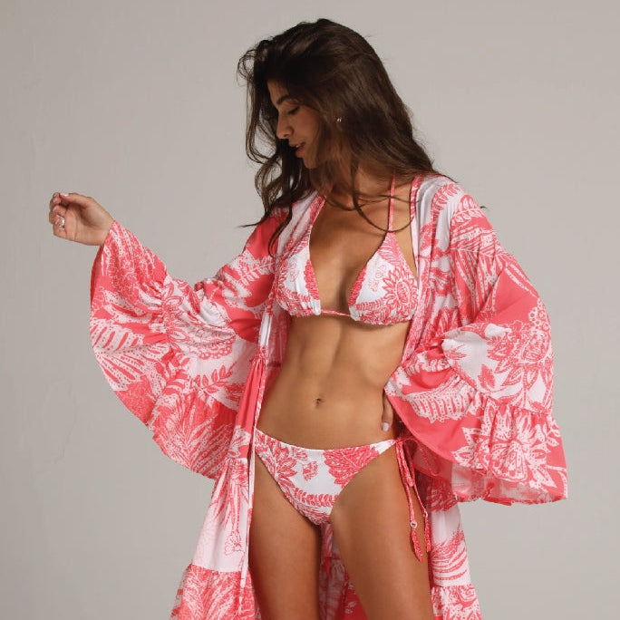 Woman wearing a red and white floral bikini with matching cover-up against a neutral background