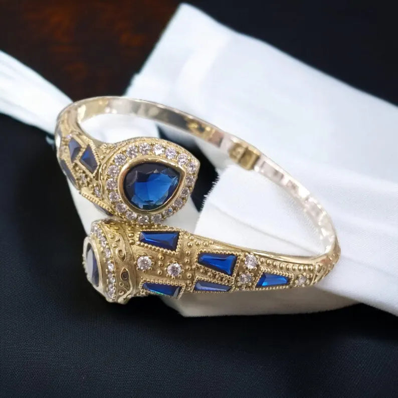 Gold bracelet with blue gemstones on a white surface