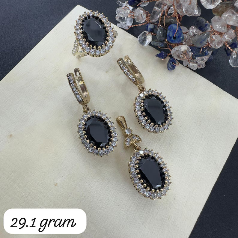 Gold and black earrings on a white surface with a weight label '29.1 gram'.