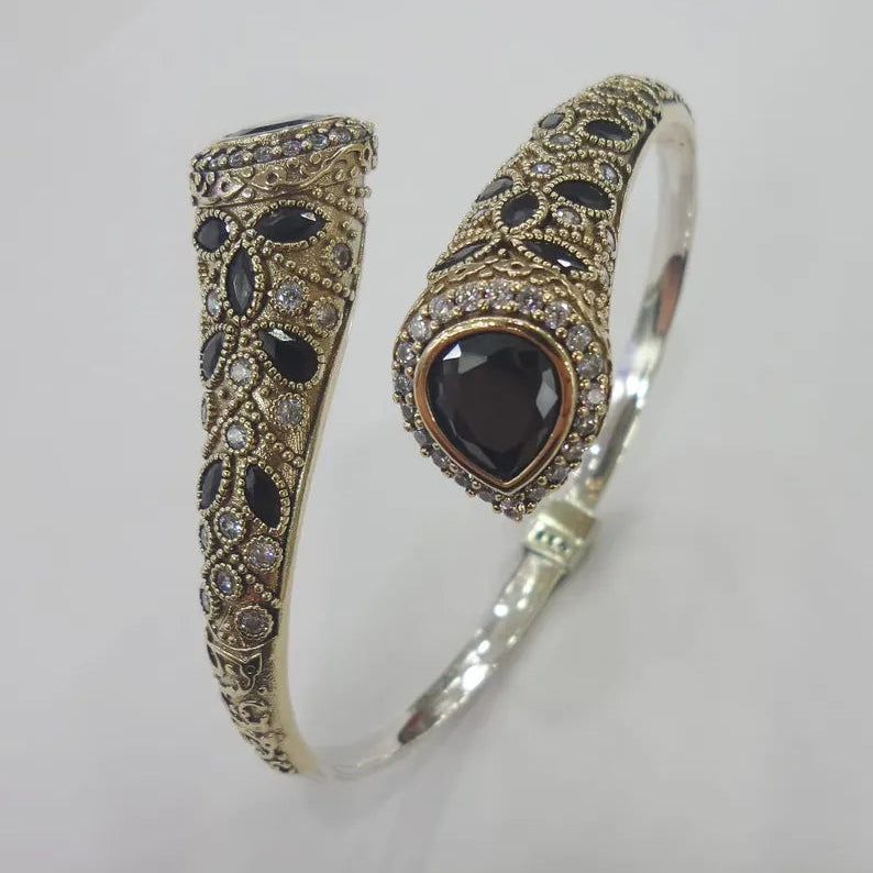 Two ornate bracelets with black stones on a light gray background