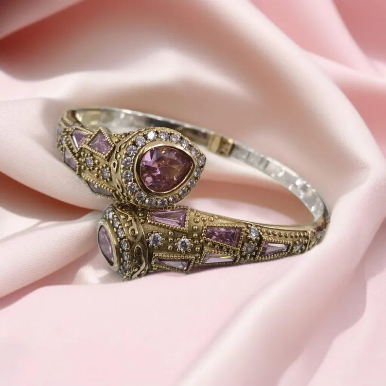 Ornate ring with purple gemstones on a pink fabric background