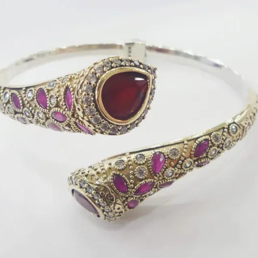 Ornate bracelet with red gemstone and purple stones on a white background