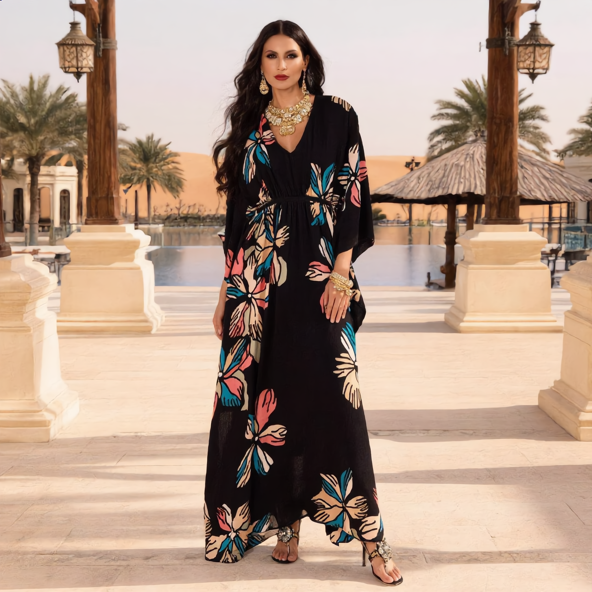 Woman in a black floral dress standing on steps with palm trees and buildings in the background