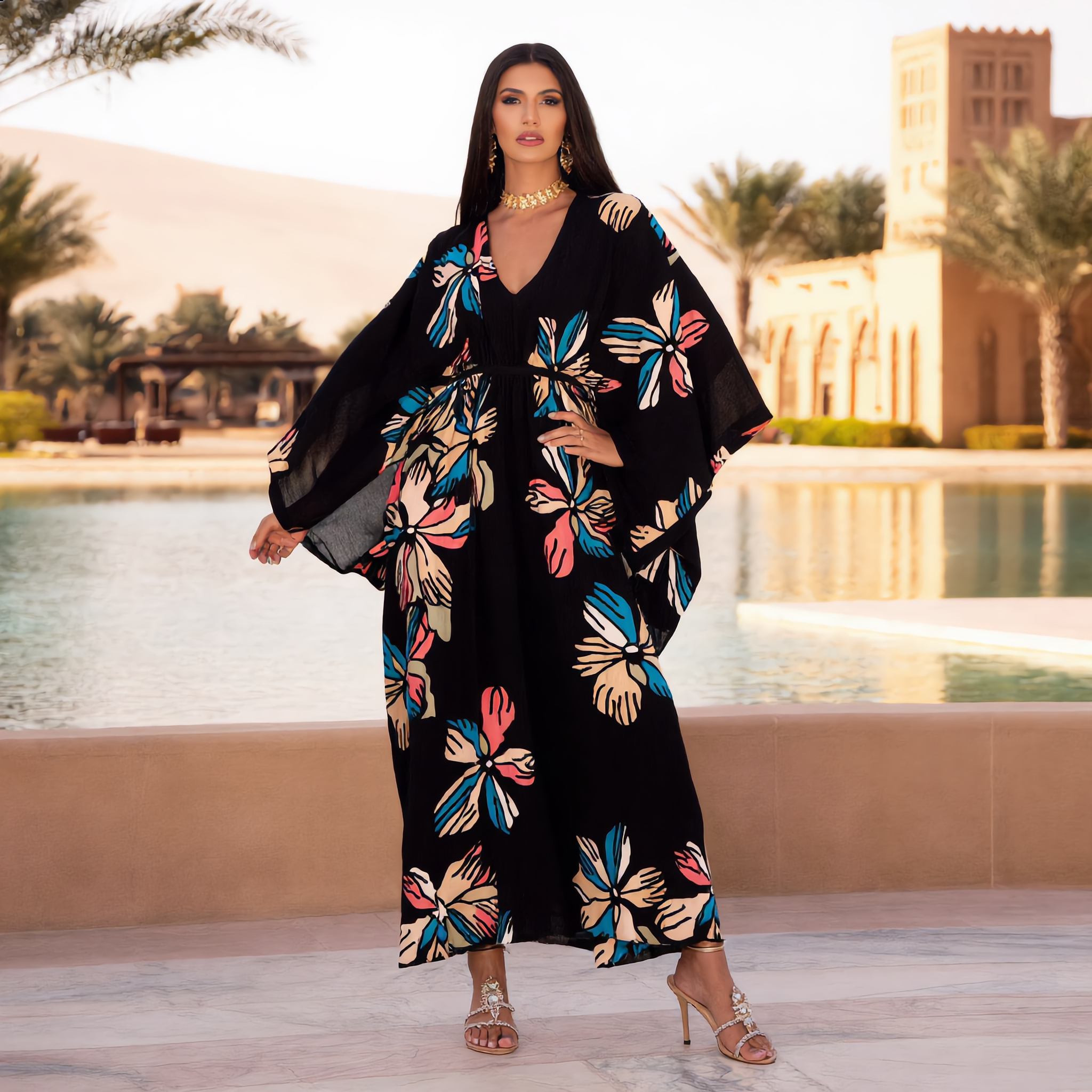 Woman wearing a black floral dress standing by a pool with a scenic background