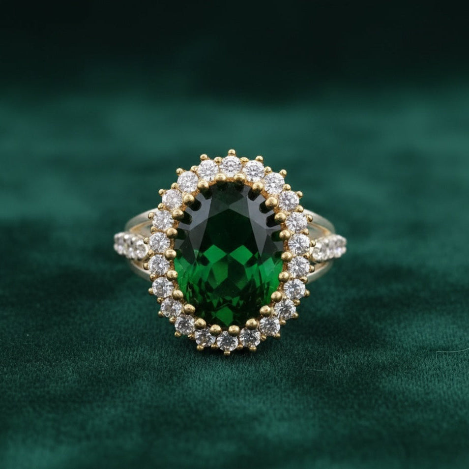 Gold ring with a green gemstone and diamond accents on a green velvet background