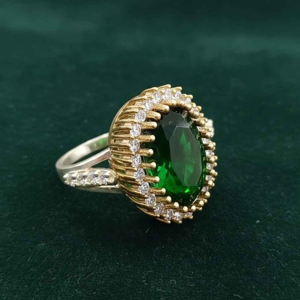Gold ring with a green gemstone on a dark green background