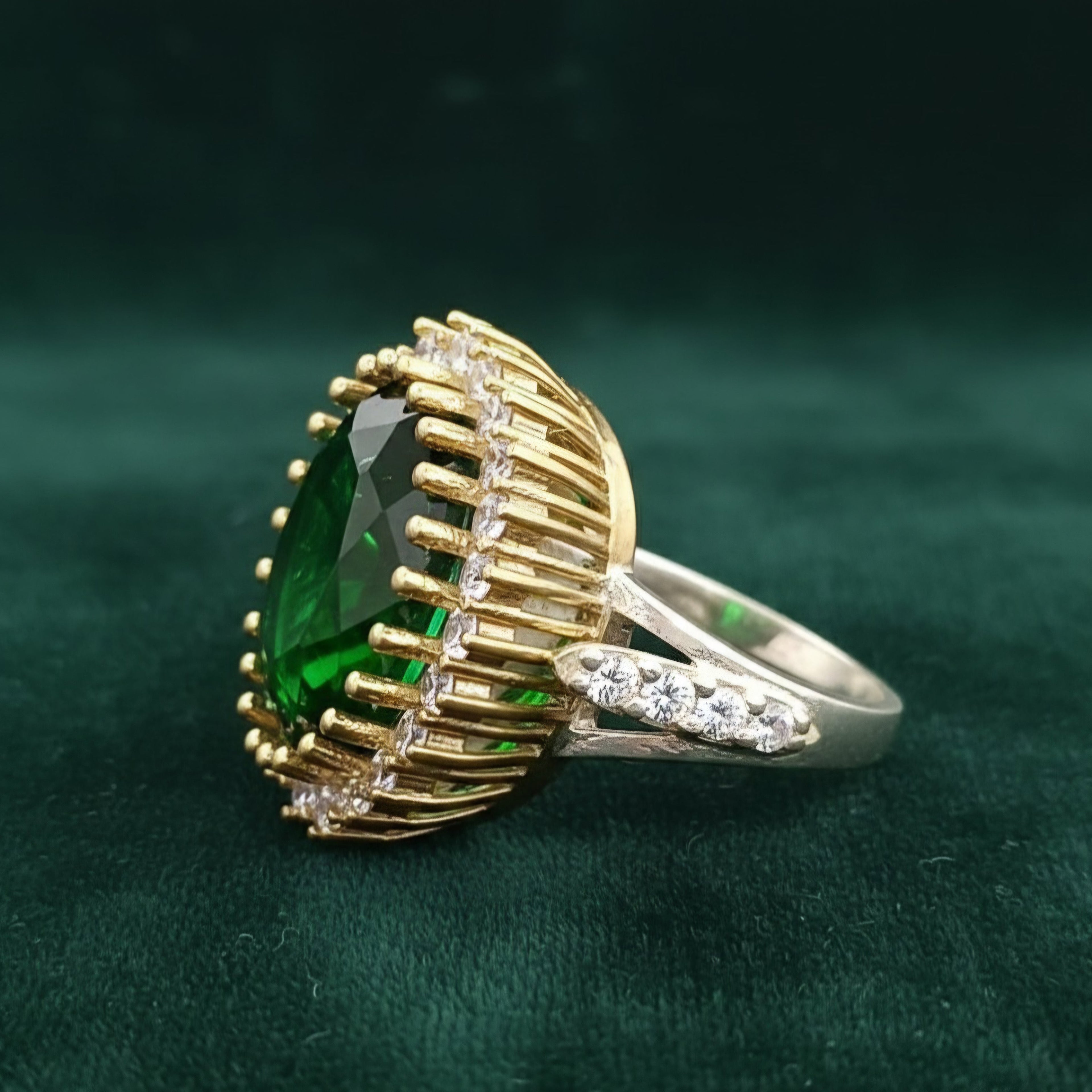 Gold and silver ring with a green gemstone on a dark green background