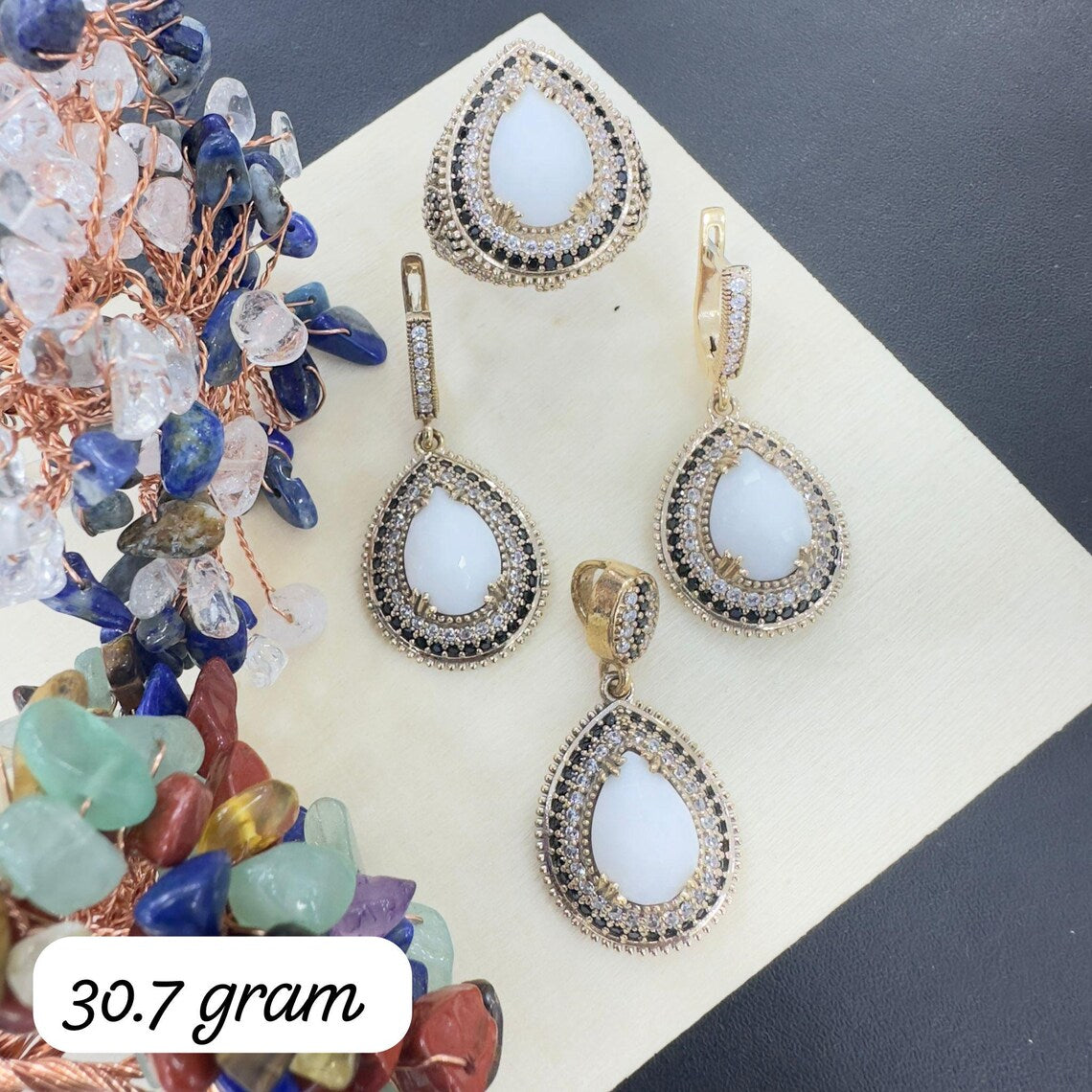Teardrop-shaped earrings with gemstones on a dark surface